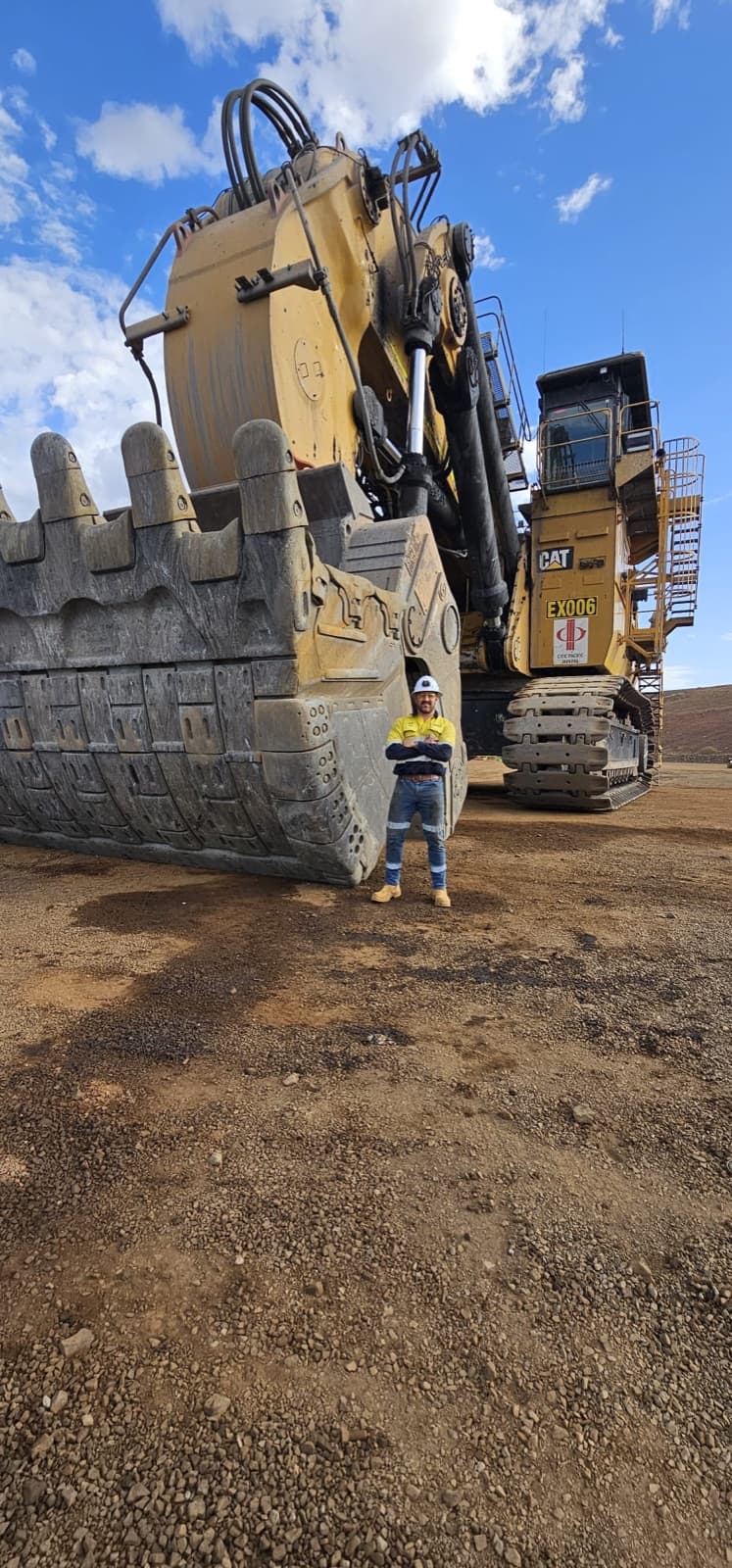 Cobi Rontaunay standing in front of a CAT mining excavator