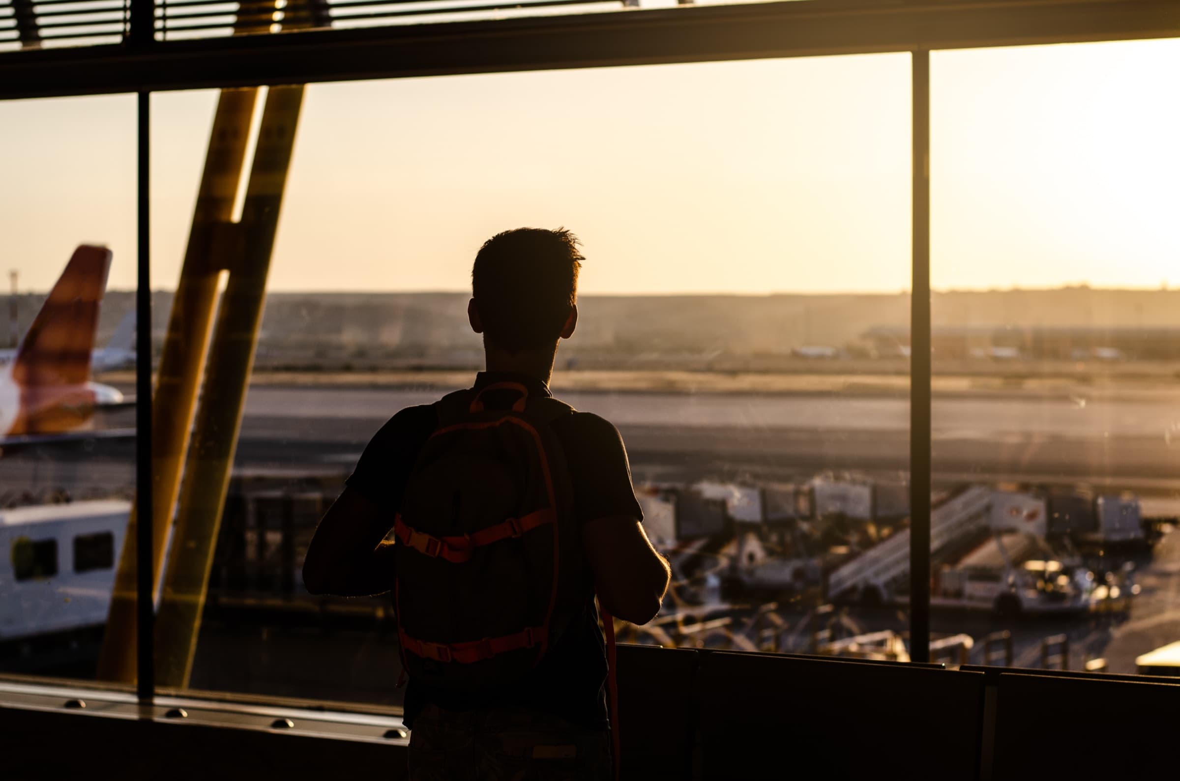 A traveller looking out over the runway from an airport window