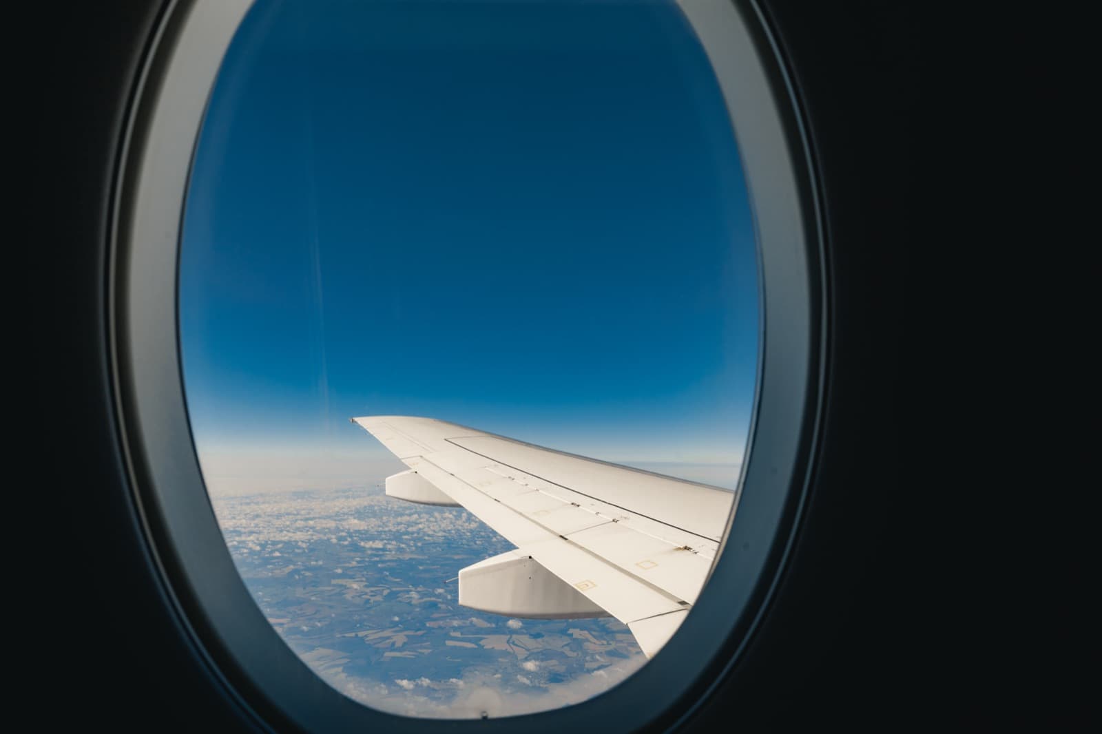 Plane wing seen from a window seat above the clouds